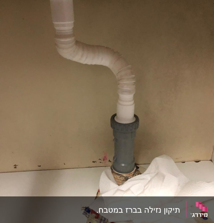 צינור פלסטיק מתחת לכיור עם ניירות